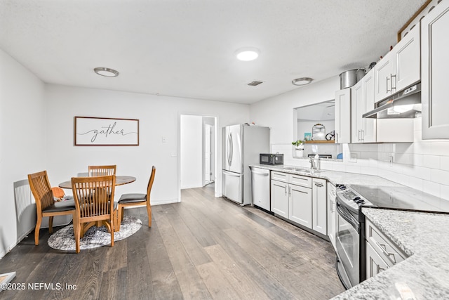 918 Arkenstone Dr, Jacksonville, FL 32225 - kitchen featuring under cabinet range hood, appliances with stainless steel finishes, a sink, light stone countertops, and wood finished floors