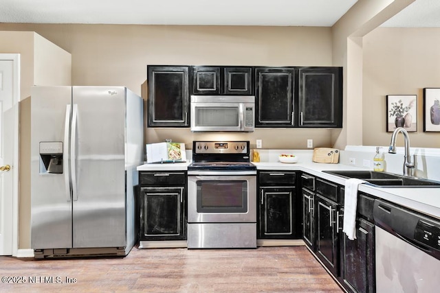 7990 Baymeadows Rd E Unit 2006, Jacksonville, FL 32256 - kitchen featuring appliances with stainless steel finishes, dark cabinetry, a sink, light countertops, and light wood finished floors