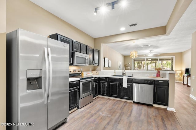 7990 Baymeadows Rd E Unit 2006, Jacksonville, FL 32256 - kitchen with stainless steel appliances, a sink, a peninsula, dark cabinets, and light wood finished floors