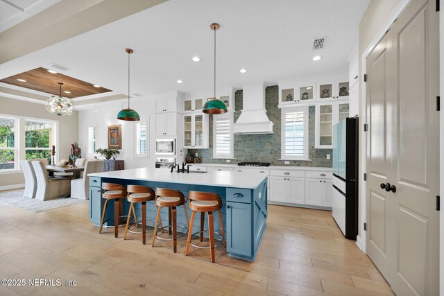 71 Deer Ridge Dr, Ponte Vedra, FL 32081 - kitchen featuring custom range hood, freestanding refrigerator, white microwave, light countertops, and white cabinets