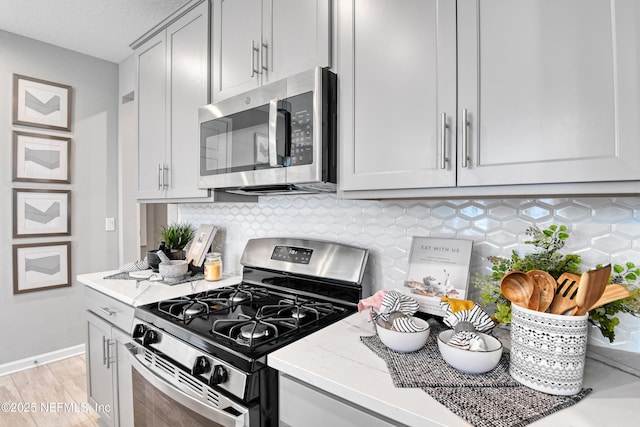 95 Elm Creek Dr, Saint Augustine, FL 32092 - kitchen with appliances with stainless steel finishes, backsplash, baseboards, light wood-type flooring, and gray cabinets