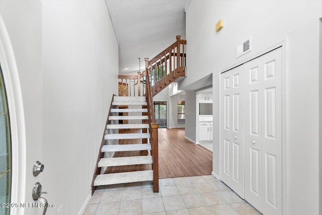 5524 Manfields Pl, Jacksonville, FL 32207 - stairs featuring tile patterned floors, a high ceiling, baseboards, and a textured ceiling