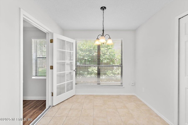 5524 Manfields Pl, Jacksonville, FL 32207 - unfurnished dining area with a chandelier, a textured ceiling, light tile patterned floors, and baseboards