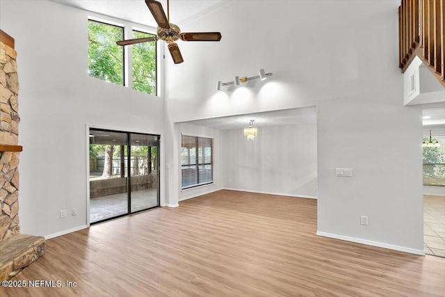 5524 Manfields Pl, Jacksonville, FL 32207 - unfurnished living room featuring a chandelier, ceiling fan, light wood finished floors, a high ceiling, and baseboards