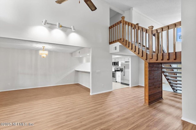 5524 Manfields Pl, Jacksonville, FL 32207 - unfurnished living room featuring wood finished floors, a high ceiling, stairs, a ceiling fan, and a chandelier