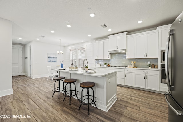 85 Park Center Ave, Ponte Vedra, FL 32081 - kitchen with appliances with stainless steel finishes, light wood-style flooring, a kitchen breakfast bar, light countertops, and a kitchen island with sink