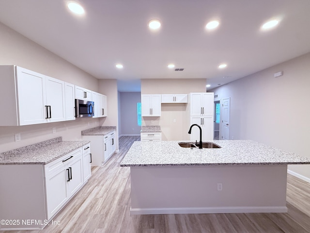 6971 Como Rd, Jacksonville, FL 32210 - kitchen featuring stainless steel microwave, a sink, light wood-style floors, light stone countertops, and recessed lighting