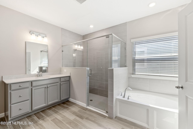 2724 White Cedar Ln, Green Cove Springs, FL 32043 - full bath featuring vanity, a garden tub, a shower stall, wood finished floors, and recessed lighting