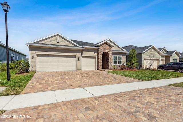 2724 White Cedar Ln, Green Cove Springs, FL 32043 - single story home featuring a front lawn, decorative driveway, stone siding, and a garage