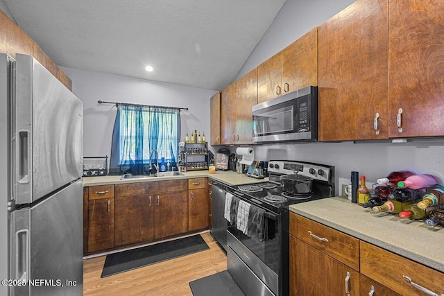 734 N Walnut St, Starke, FL 32091 - kitchen with appliances with stainless steel finishes, a sink, light wood finished floors, vaulted ceiling, and light countertops