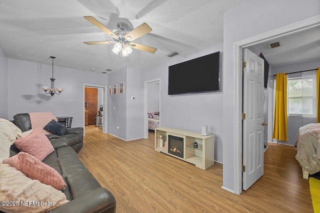 734 N Walnut St, Starke, FL 32091 - living area featuring a textured ceiling, light wood-type flooring, a ceiling fan, and a chandelier