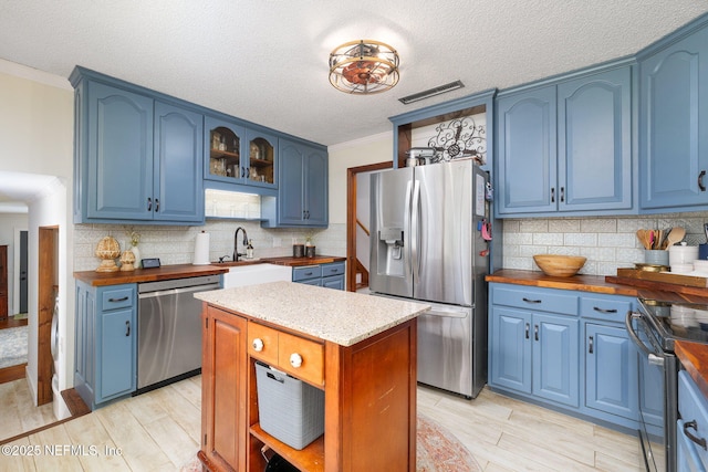 17459 Eagle Bend Blvd, Jacksonville, FL 32226 - kitchen with appliances with stainless steel finishes, blue cabinetry, a sink, a textured ceiling, and decorative backsplash