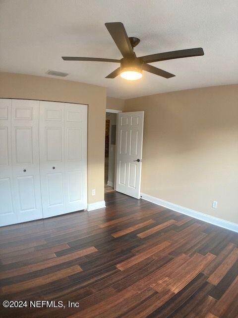 5615 San Juan Ave Unit 310, Jacksonville, FL 32210 - unfurnished bedroom with baseboards, dark wood-style floors, a closet, and a ceiling fan
