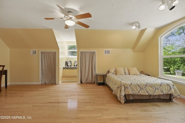 2708 Poinsettia Ave, Middleburg, FL 32068 - bedroom with a textured ceiling, light wood-type flooring, vaulted ceiling, multiple windows, and baseboards