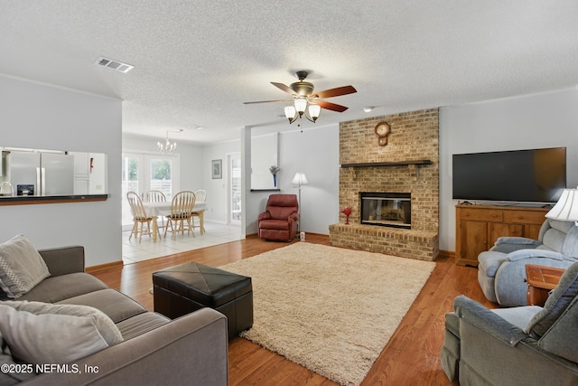 2708 Poinsettia Ave, Middleburg, FL 32068 - living room with a chandelier, a ceiling fan, wood finished floors, a brick fireplace, and a textured ceiling