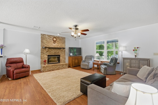 2708 Poinsettia Ave, Middleburg, FL 32068 - living room with a ceiling fan, a textured ceiling, light wood-style flooring, and a fireplace
