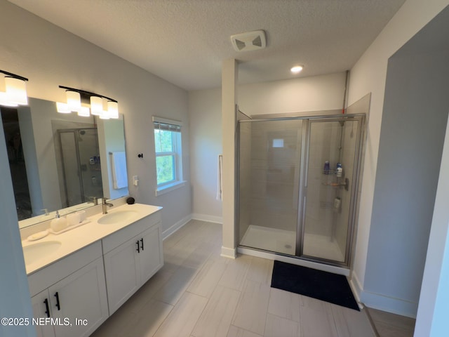 10065 Element Rd, Jacksonville, FL 32256 - bathroom with a shower stall, a textured ceiling, double vanity, and baseboards