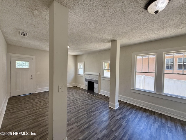 725 Calvert St, Jacksonville, FL 32208 - unfurnished living room featuring dark wood-style floors, a textured ceiling, baseboards, plenty of natural light, and a premium fireplace