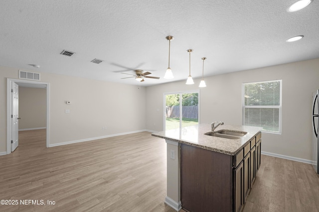 7529 Hare Ave, Jacksonville, FL 32211 - kitchen featuring a sink, light wood-type flooring, a ceiling fan, dark brown cabinetry, and a textured ceiling