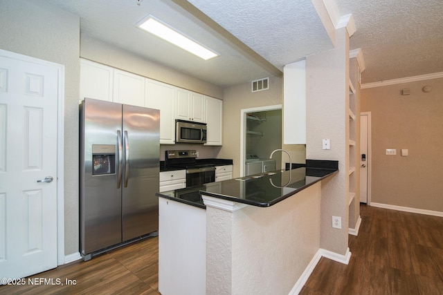 8539 W Gate Pkwy Unit 424, Jacksonville, FL 32216 - kitchen with appliances with stainless steel finishes, separate washer and dryer, a peninsula, white cabinets, and dark wood-type flooring