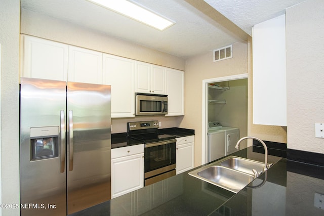 8539 W Gate Pkwy Unit 424, Jacksonville, FL 32216 - kitchen with appliances with stainless steel finishes, washer and dryer, a sink, dark countertops, and white cabinets