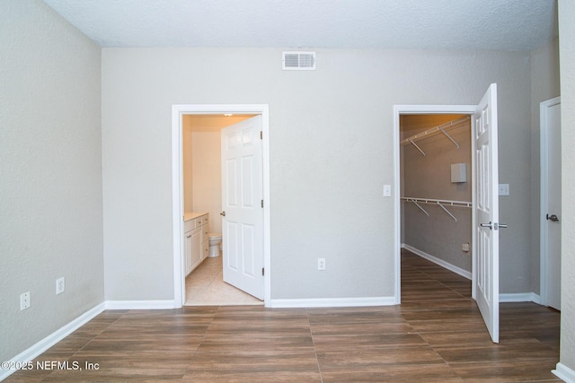 8539 W Gate Pkwy Unit 424, Jacksonville, FL 32216 - unfurnished bedroom with a walk in closet, ensuite bath, wood finished floors, a closet, and baseboards