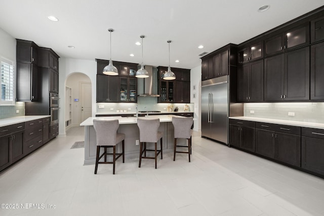 465 Deer Valley Dr, Ponte Vedra, FL 32081 - kitchen featuring wall chimney range hood, appliances with stainless steel finishes, arched walkways, backsplash, and light countertops