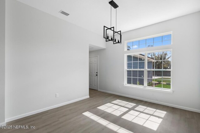 7830 Smart Ave, Jacksonville, FL 32219 - unfurnished dining area with a chandelier, wood finished floors, plenty of natural light, baseboards, and a high ceiling