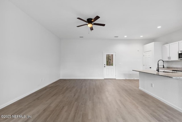 7830 Smart Ave, Jacksonville, FL 32219 - unfurnished living room featuring a ceiling fan, light wood-style flooring, baseboards, a sink, and recessed lighting
