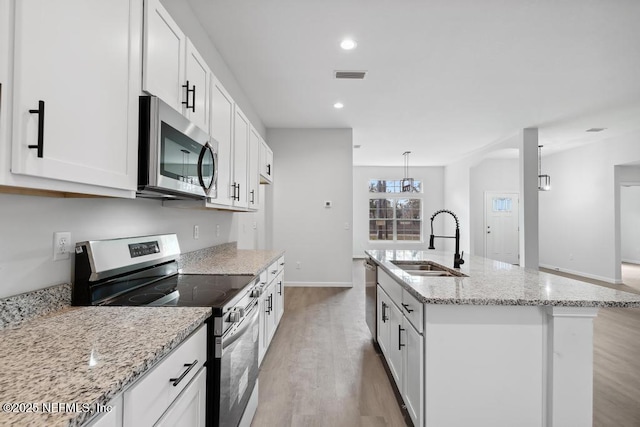 7830 Smart Ave, Jacksonville, FL 32219 - kitchen featuring stainless steel appliances, a sink, light wood-style floors, white cabinets, and an island with sink