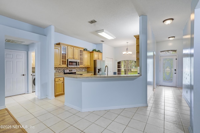 3784 Charles Green Rd, Hilliard, FL 32046 - kitchen featuring stainless steel appliances, a chandelier, a peninsula, washer / dryer, and light countertops
