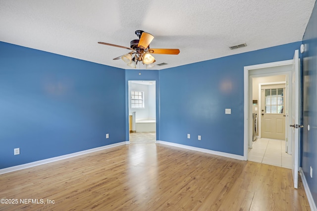 3784 Charles Green Rd, Hilliard, FL 32046 - empty room with ceiling fan, a textured ceiling, light wood-style floors, baseboards, and washer / clothes dryer