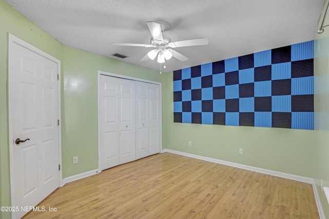 3784 Charles Green Rd, Hilliard, FL 32046 - unfurnished bedroom with an accent wall, baseboards, wood finished floors, wallpapered walls, and a textured ceiling