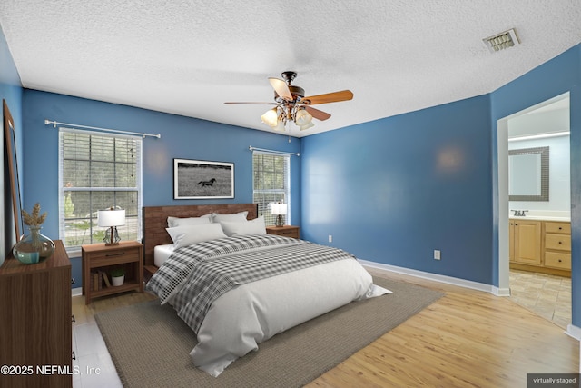 3784 Charles Green Rd, Hilliard, FL 32046 - bedroom featuring a textured ceiling, baseboards, a ceiling fan, light wood finished floors, and connected bathroom