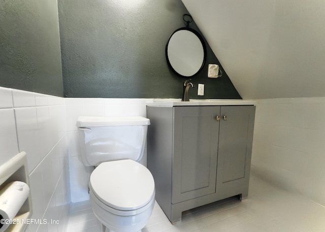 1344 Degrove Rd, Saint Johns, FL 32259 - half bath featuring toilet, vanity, tile patterned flooring, tile walls, and a wainscoted wall