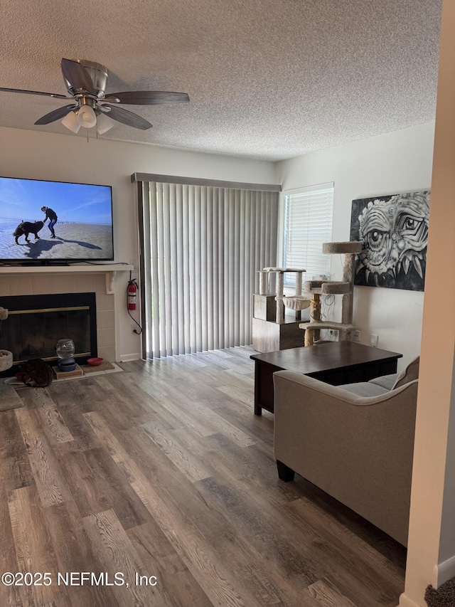 200 Spindrift Ln, Neptune Beach, FL 32266 - living area with a tiled fireplace, wood finished floors, a textured ceiling, and ceiling fan