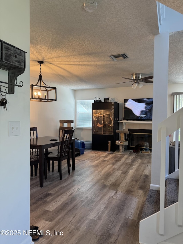 200 Spindrift Ln, Neptune Beach, FL 32266 - dining space featuring a textured ceiling, wood finished floors, a ceiling fan, a glass covered fireplace, and a chandelier