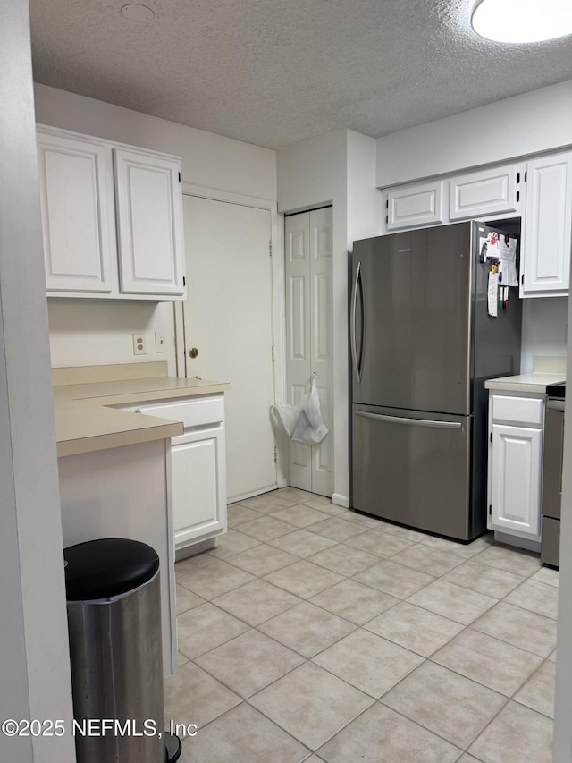 200 Spindrift Ln, Neptune Beach, FL 32266 - kitchen with freestanding refrigerator, a textured ceiling, white cabinets, light countertops, and stove