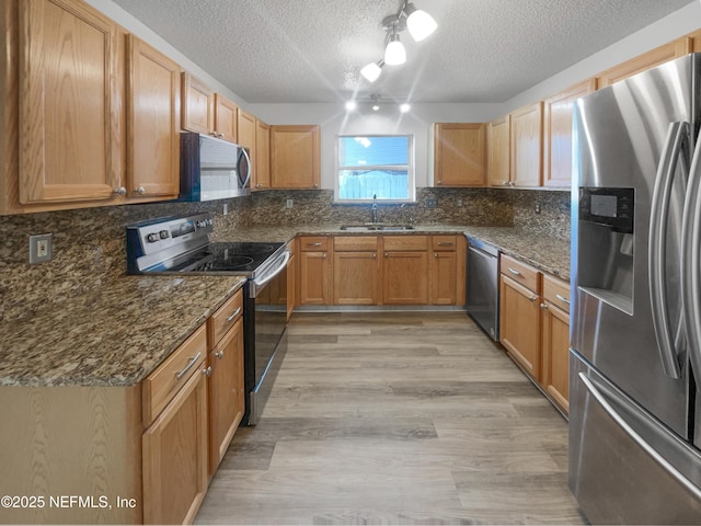 12011 Cobblestone Forest Cir S, Jacksonville, FL 32225 - kitchen featuring appliances with stainless steel finishes, a sink, a textured ceiling, decorative backsplash, and dark stone counters