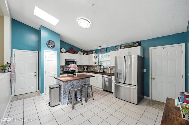 1537 Elmar Rd, Jacksonville, FL 32226 - kitchen with stainless steel appliances, lofted ceiling, wood counters, white cabinetry, and backsplash
