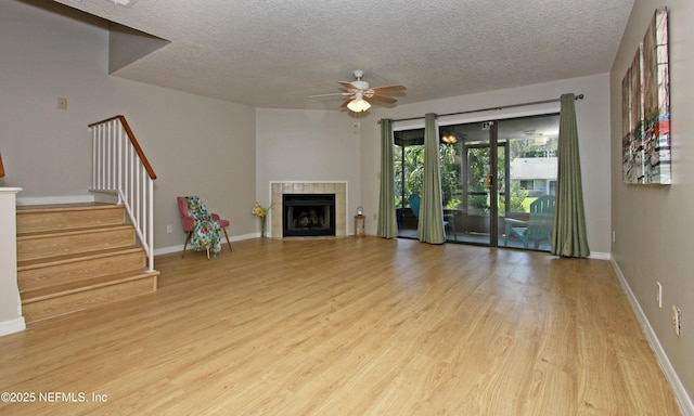 2105 Sandpiper Ct, Ponte Vedra Beach, FL 32082 - unfurnished living room with wood finished floors, a textured ceiling, ceiling fan, stairway, and a tiled fireplace