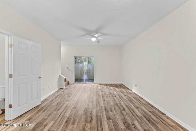 4778 Playpen Dr, Jacksonville, FL 32210 - unfurnished living room with a ceiling fan, light wood finished floors, stairway, baseboards, and a textured ceiling