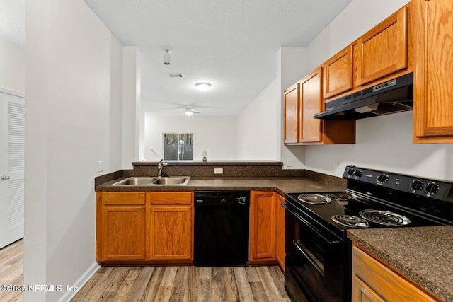 4778 Playpen Dr, Jacksonville, FL 32210 - kitchen with black appliances, under cabinet range hood, a sink, light wood finished floors, and dark countertops