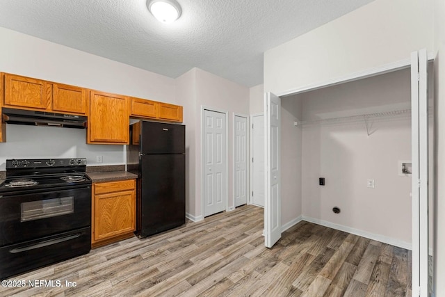 4778 Playpen Dr, Jacksonville, FL 32210 - kitchen with black appliances, under cabinet range hood, light wood-style floors, brown cabinetry, and a textured ceiling
