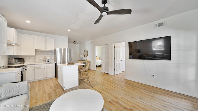 119 Moore St, Saint Augustine, FL 32084 - kitchen with a sink, under cabinet range hood, appliances with stainless steel finishes, a kitchen bar, and a center island