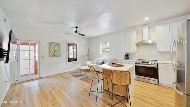 119 Moore St, Saint Augustine, FL 32084 - kitchen with appliances with stainless steel finishes, wall chimney exhaust hood, open floor plan, light wood finished floors, and recessed lighting