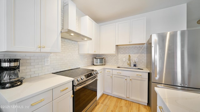119 Moore St, Saint Augustine, FL 32084 - kitchen featuring appliances with stainless steel finishes, wall chimney exhaust hood, a sink, and white cabinetry