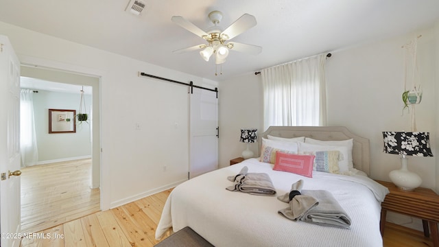 119 Moore St, Saint Augustine, FL 32084 - bedroom with a barn door, wood finished floors, multiple windows, and a ceiling fan