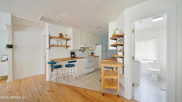 119 Moore St, Saint Augustine, FL 32084 - kitchen featuring white appliances, open shelves, white cabinets, wood counters, and light wood finished floors
