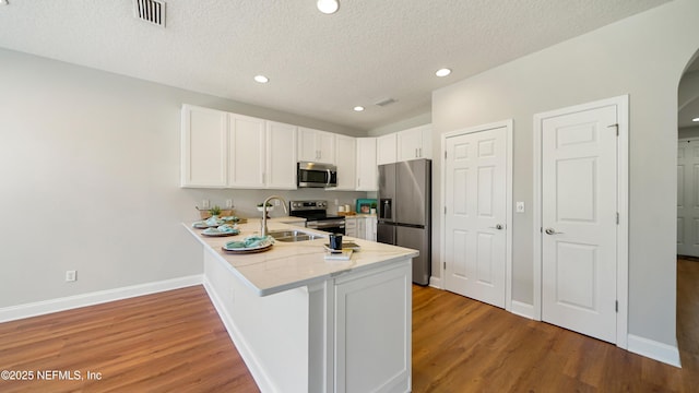 18 Amistad Dr, Saint Augustine, FL 32086 - kitchen with stainless steel appliances, a sink, a peninsula, white cabinets, and light wood-style flooring